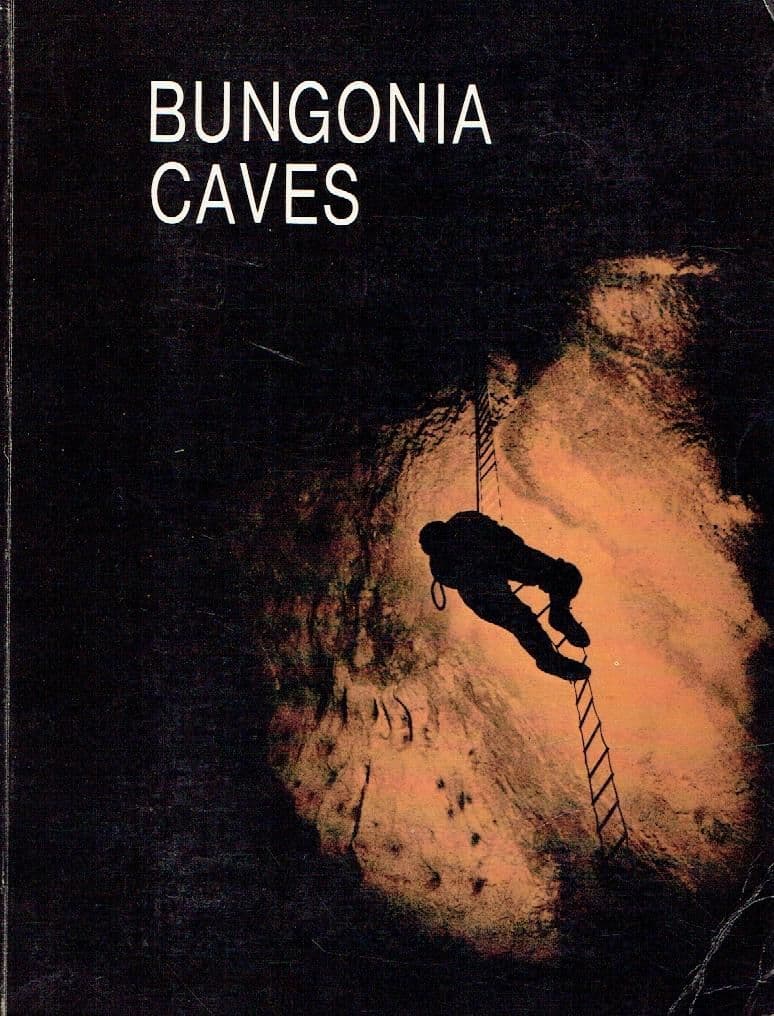 Silhouette figure descending into bungonia cave by rope lit by orange light